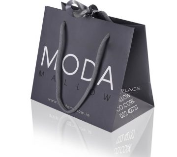 Grey small boutique luxury paper bag with middle ribbon bow and cotton rope hadle that says moda mallow