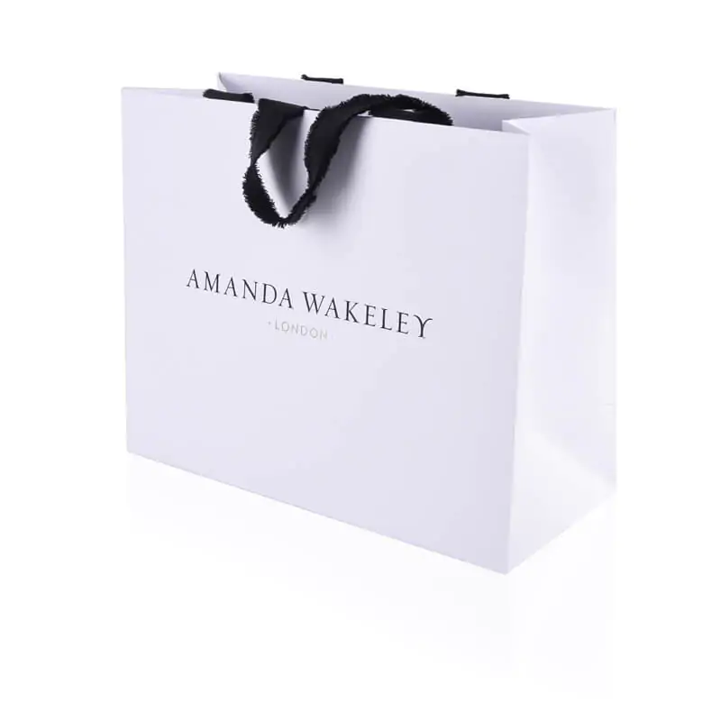 White uncoated luxury paper basg with special vanishing ribbon handle that says Amanda wakeley