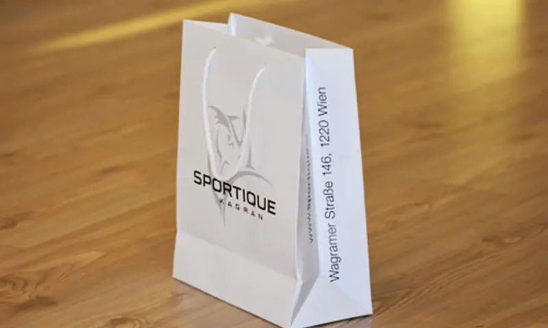 White unlaminated paper bag with white rope taht says sportique