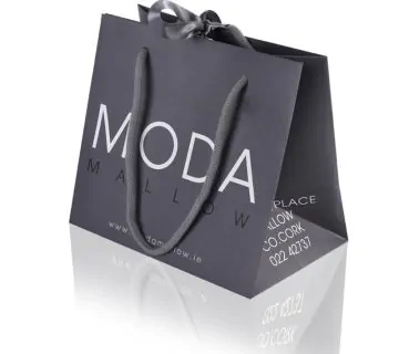 Grey small boutique luxury paper bag with middle ribbon bow and cotton rope hadle that says moda mallow